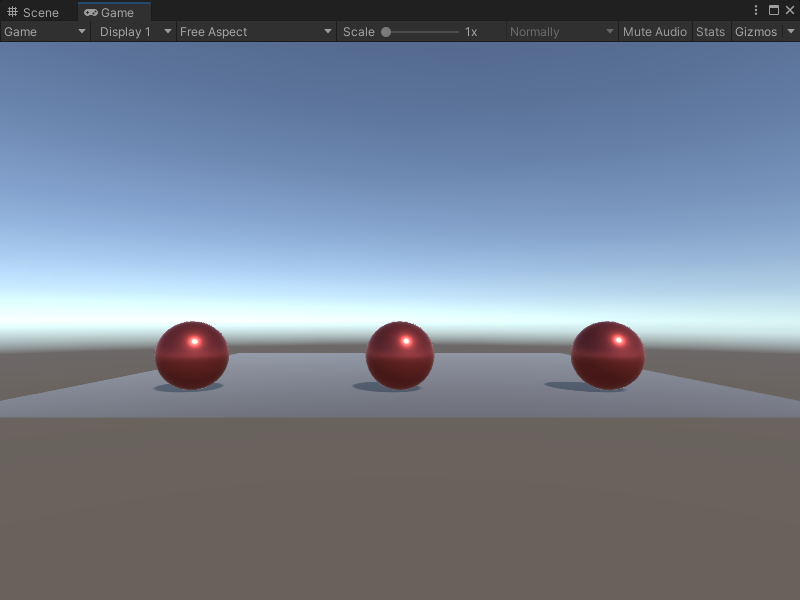 An image of the Game view. It displays 3 red metallic spheres in a line on a grey plane.